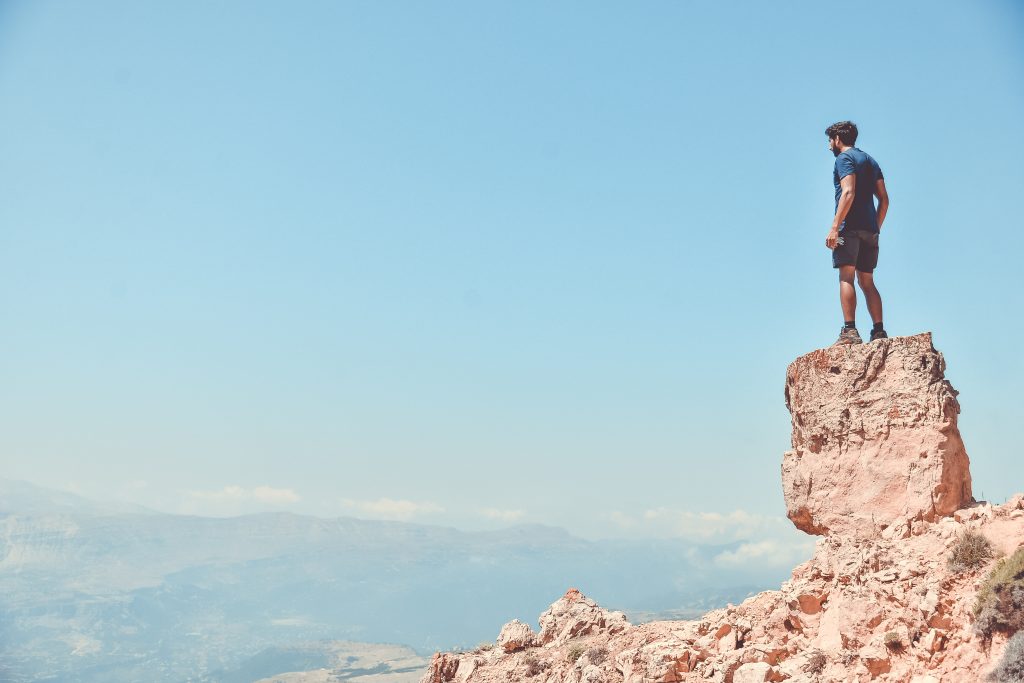 Man standing on a cliff looking off into the distance