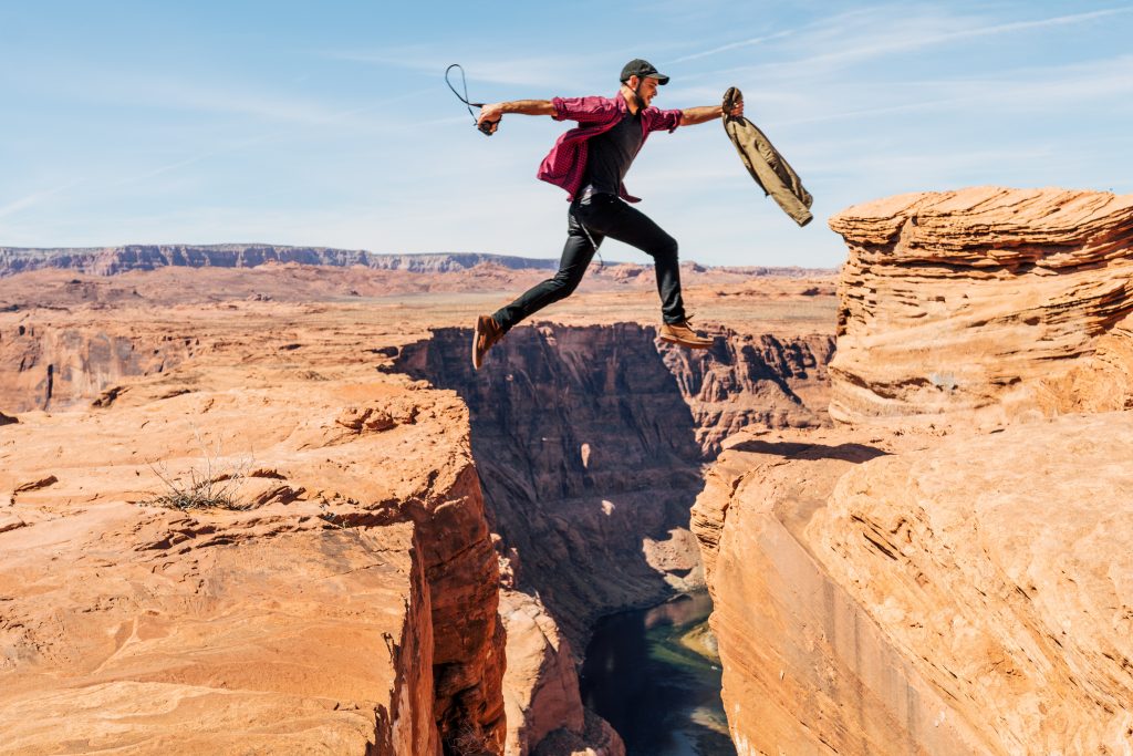 Man jumping from one side of a cliff to another