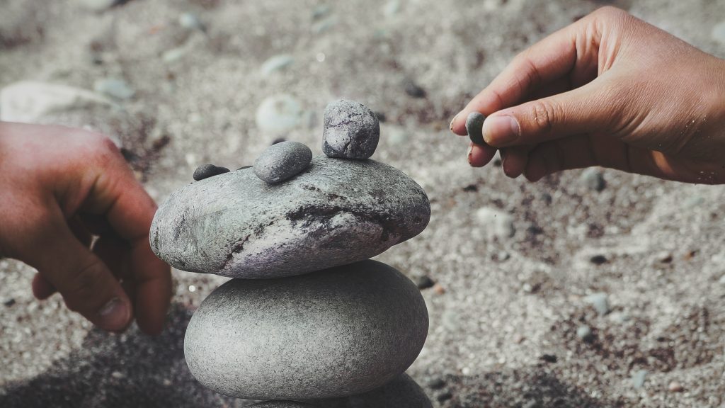 Person stacking rocks on top of each other on the beach