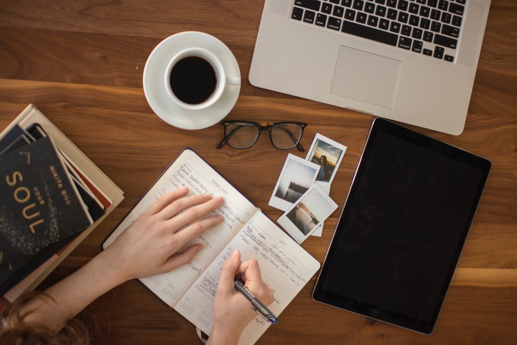 Flatlay of journal, computer, and coffee cup with writing