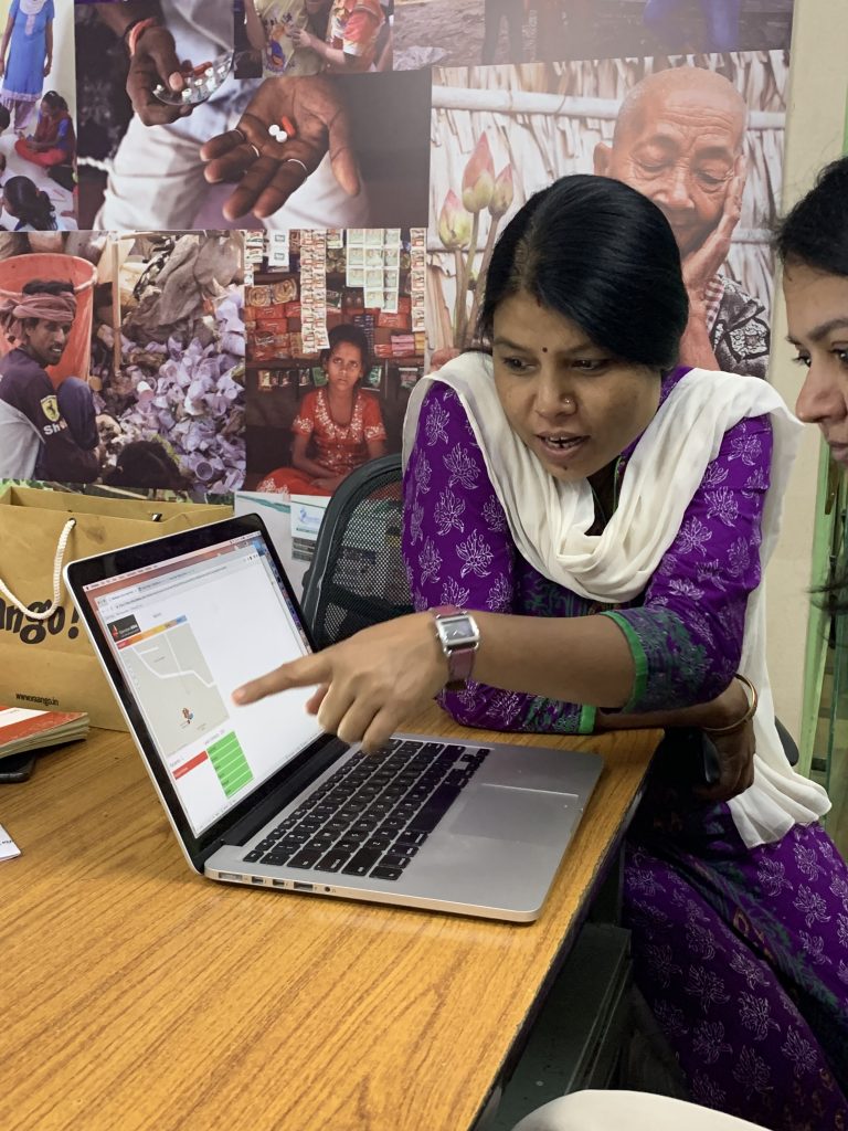 Operation ASHA staff pointing at a computer screen showing data modeled in Tableau