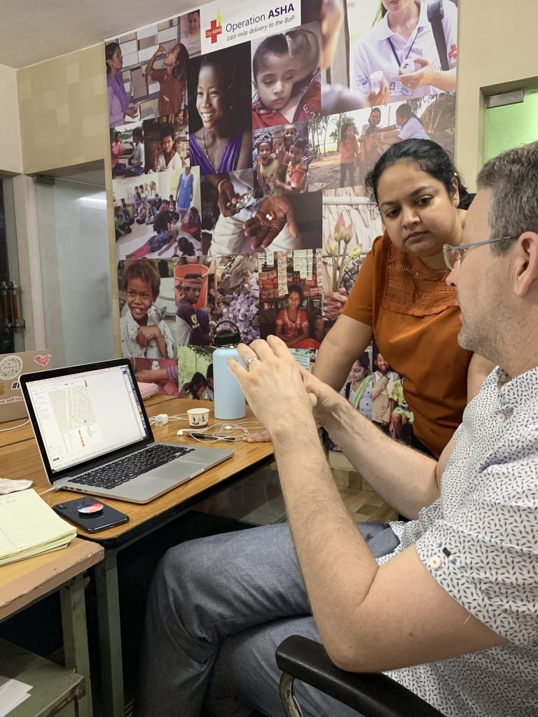 Tableau volunteer Michael and Operation ASHA staff looking at a computer discussing data modeling options
