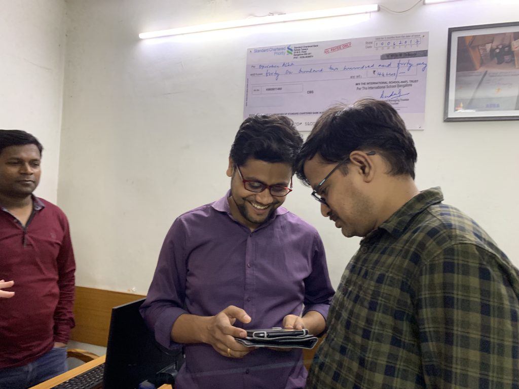 Operation ASHA staff smiling at a tablet with the Tableau app